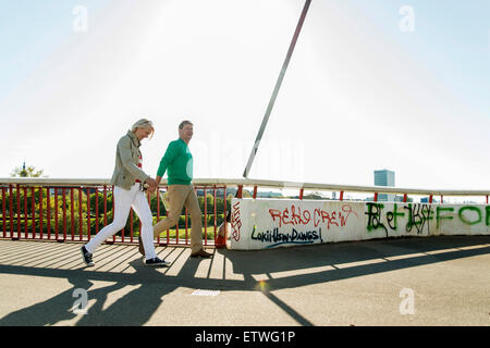 Allemagne, Mannheim, couple d'âge mûr crossing bridge, holding hands Banque D'Images