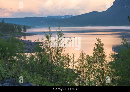 L'aube à Stora sjöfallets parc national avec soleil se reflétant dans l'eau et montagnes en arrière-plan à Gällivare tour suédois Banque D'Images