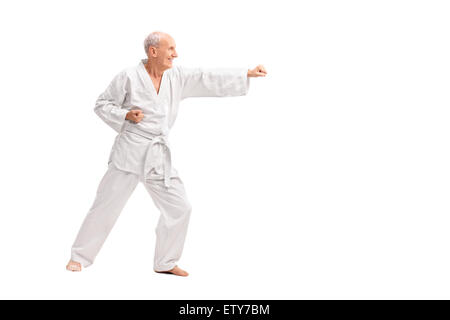 Profil de pleine longueur tourné d'un vieil homme dans un kimono blanc pratiquer le karaté isolé sur fond blanc Banque D'Images