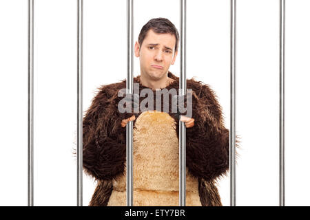 Portrait d'un jeune homme triste dans un costume d'ours debout derrière les barreaux dans une cellule isolée sur fond blanc Banque D'Images