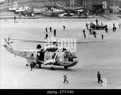 Sauvetage au large de la mer du port de Cullercoats dans des vents de force 7. Le double sauvetage d'un bateau de pêche et puis les petites embarcations de sauvetage côtier. Les Sea King de sauvetage par hélicoptère (un homme sur la plage après avoir été arrachés de la mer. Dans l'arrière-plan la pêche côtière Banque D'Images