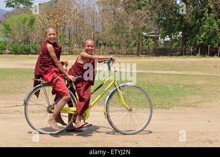 Deux jeunes moines birmans à vélo dans un village du lac Inle, Birmanie, Myanmar, Asie du Sud-est Banque D'Images