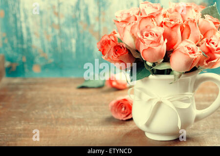 Roses roses dans un pot sur fond bleu Banque D'Images