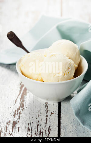 Glace vanille boules en coupe blanc sur fond de bois Banque D'Images