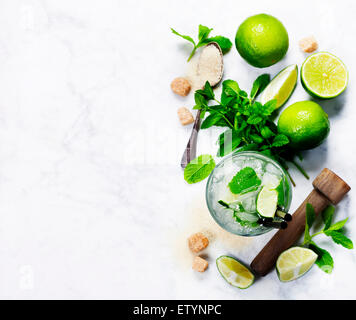 Ingrédients pour faire les mojitos (cubes de glace, de feuilles de menthe, de sucre et de citron vert sur fond rustique) Banque D'Images