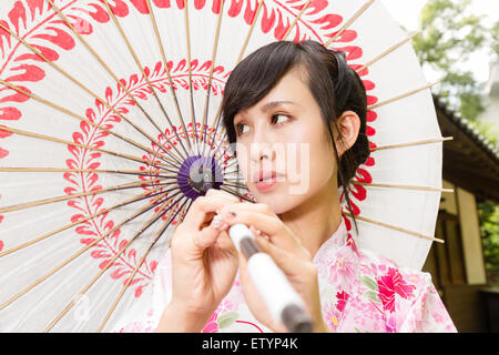 Asian woman wearing un kimono à l'avant de la maison japonaise holding umbrella Banque D'Images