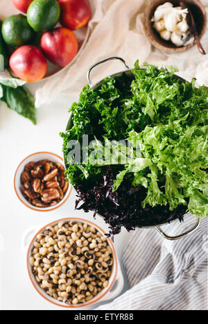 Salade verte feuilles sont afficher avec d'autres ingrédients de pêches, limes, et dolique à oeil noir sur fond blanc. Banque D'Images