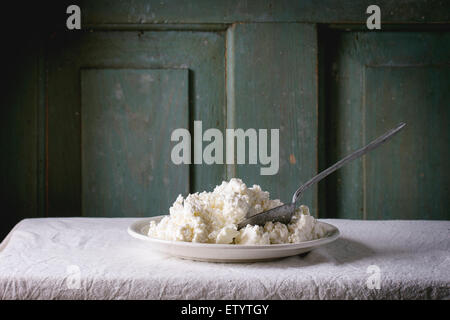 Assiette de fromage fait maison sur nappe blanche avec fond en bois turquoise. Atmosphère rustique foncé. Banque D'Images