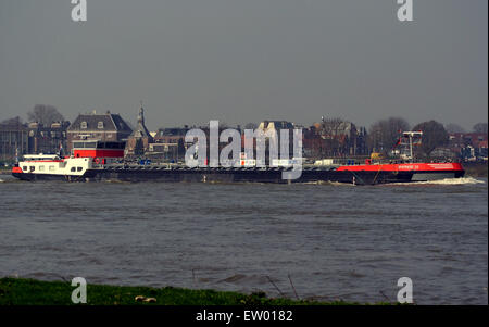 Le Synthese 15 est un navire-citerne immatriculé ENI 02329557. Ce navire navigue sur la rivière Waal aux pays-Bas, démontrant son rôle vital dans le transport de pétrole et d'autres marchandises. L'image illustre la structure massive et la fonctionnalité opérationnelle du navire alors qu'il manœuvre dans les eaux du fleuve, un acteur clé de l'industrie maritime de la région. Banque D'Images