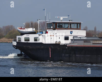 L'image représente le Tancar, ENI 02006909, un navire-citerne opérant dans le Noordzeekanaal, port d'Amsterdam. La scène illustre l'activité animée du port, avec l'accostage et le déchargement de grands navires, vitaux pour le commerce et le transport maritimes. Banque D'Images