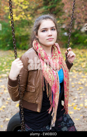 Teenage girl sitting on a swing à l'extérieur Banque D'Images