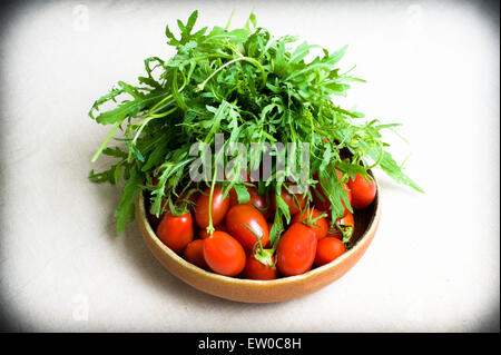 Salade verte et tomates rouges matières sur plaque sur fond neutre Banque D'Images