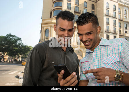 Deux amis d'Amérique latine using cell phone outdoors Banque D'Images