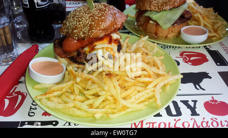 Vue d'un énorme hamburger hamburger avec frites, œufs, saucisses, bacon et sauce barbecue accompagné de frites et de la sauce. Banque D'Images