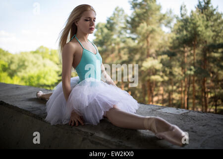 Ballerine gracieuse en tutu blanc assis sur les groupes Banque D'Images