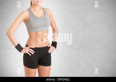 Fit woman debout avec son bras à sa taille, isolé en gris Banque D'Images