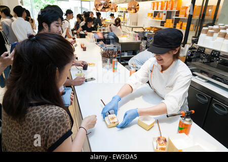 Personnel de la nouvelle pâtisserie ''Dominique Ansel Bakery'' prendre des commandes à partir de la presse membres durant la phase pré-événement d'ouverture pour la première boulangerie magasin japonais situé dans Omotesando Hills le 17 juin 2015, Tokyo, Japon. La nouvelle marque est connue pour ses pâtisseries Cronuts ; un croissant doughnut création fusion par le Chef Dominique Ansel et est déjà très populaire à New York. C'est la première fois qu'il ouvrira une succursale internationale. Le Japon a connu un boom récent dans les détaillants alimentaires surtout d'essayer d'être la dernière nouvelle tendance à Tokyo. Le magasin ouvre ses portes à la population le Ju Banque D'Images