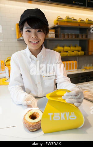 Un membre du personnel montre un Cronut durant la phase pré-événement d'ouverture de la nouvelle pâtisserie ''Dominique Ansel Bakery'' dans Omotesando Hills le 17 juin 2015, Tokyo, Japon. La nouvelle marque est connue pour ses pâtisseries Cronuts ; un croissant doughnut création fusion par le Chef Dominique Ansel et est déjà très populaire à New York. C'est la première fois qu'il ouvrira une succursale internationale. Le Japon a connu un boom récent dans les détaillants alimentaires surtout d'essayer d'être la dernière nouvelle tendance à Tokyo. Le magasin ouvre ses portes au public le 20 juin et les lignes longues sont attendus. (Photo par Rodrig Banque D'Images