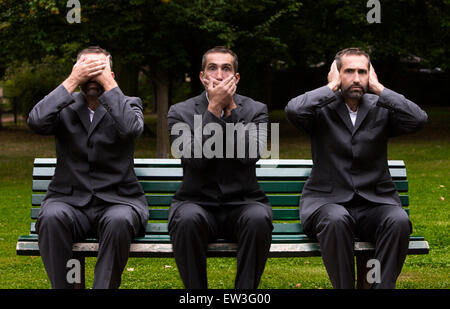 Businessman assis sur un banc, trois fois couvrant ses oreilles, les yeux et la bouche Banque D'Images