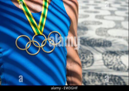 RIO DE JANEIRO, Brésil - le 23 février 2015 : Athlète portant des anneaux olympiques médaille d'or en vertu de l'article palm shadows à Ipanema. Banque D'Images