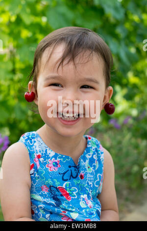 Petite fille douce avec cherry earrings Banque D'Images