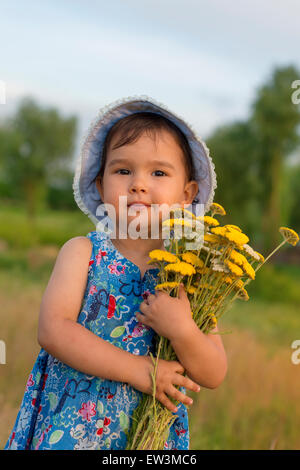 Cute little girl holding un seau de fleurs de millefeuille Banque D'Images