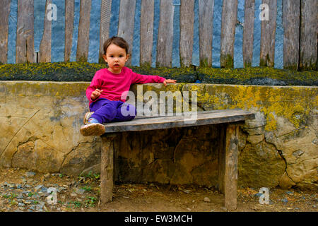 Deux ans fille assise sur banc rustique Banque D'Images