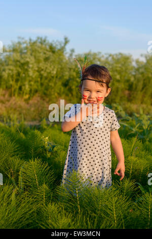 Funny little girl comme indien avec plumes et maracas Banque D'Images