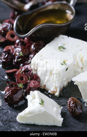 Ensemble et olives noires et le bloc de fromage feta à l'huile d'olive sur l'ardoise noire sur fond sombre. Selective focus Banque D'Images