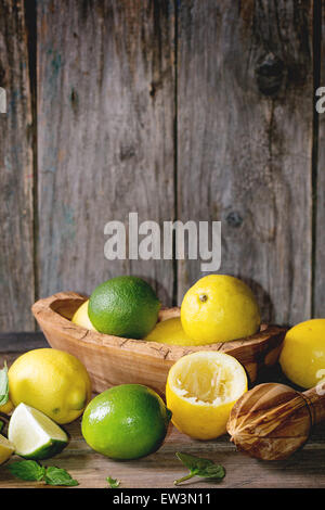 Tas d'ensemble et les tranches de citrons et limes bol en bois d'agrumes et de l'aléseur fond de bois Banque D'Images