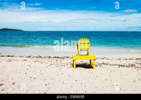 Une bouteille de bière Corona est coincé dans le sable à proximité d'une chaise de sauveteur vide face à la mer et Buck Island, Sainte-Croix, USVI. Banque D'Images