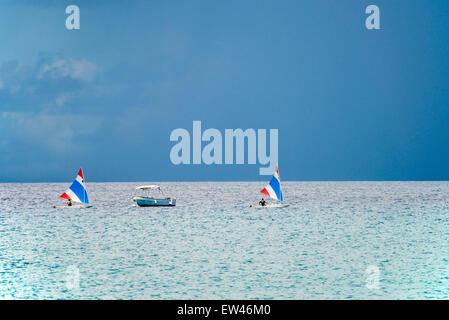 Deux petits voiliers Voile passé ancré un bateau à moteur dans les Caraïbes, avec un ciel orageux. Banque D'Images