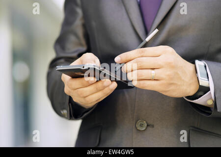 Gros plan du businessman typing note sur téléphone mobile. L'homme a une smartwatch et utilise un stylet pour écrire sur son smartphone Banque D'Images