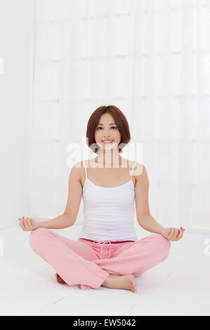 Young woman practicing yoga et smiling at the camera Banque D'Images