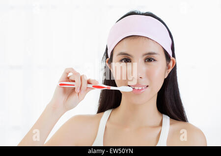 Jeune femme se brosser les dents avec le sourire Banque D'Images