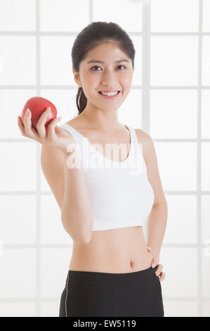 Jeune femme tenant une pomme rouge et smiling at the camera Banque D'Images