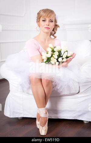 Ballerine magnifique avec des fleurs assis sur une chaise Banque D'Images