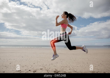 Les os des jambes en surbrillance de femme jogging on beach Banque D'Images