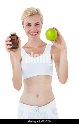 Monter blond woman holding medicine et pomme verte Banque D'Images