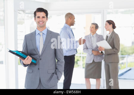 Smiling businessman holding files and looking at camera Banque D'Images