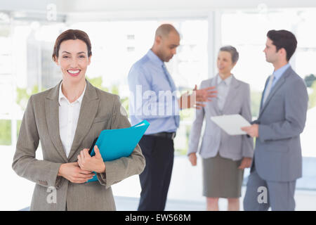 Smiling businesswoman holding files and looking at camera Banque D'Images