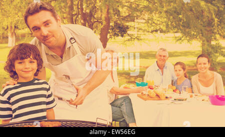 Père et fils à barbecue avec family having lunch in park Banque D'Images