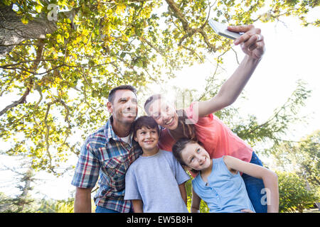 Famille heureuse dans le parc prendre selfies Banque D'Images