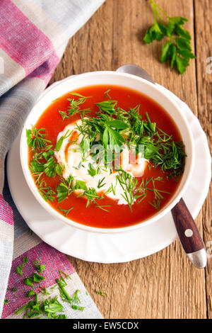 Soupe froide de tomates faites maison avec du fromage à la crème et fines herbes sur table en bois rustique Banque D'Images