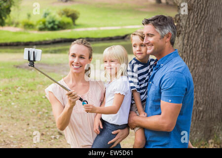 Famille heureuse à l'aide d'un bâton selfies dans le parc Banque D'Images