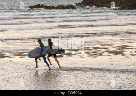 Deux surfeurs en marche dans la mer à la plage de Fistral, Newquay, Cornwall. UK. Banque D'Images