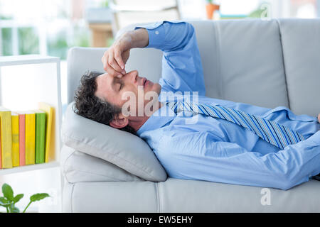 Inquiets businessman with head in hands lying on couch Banque D'Images