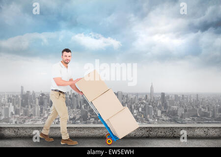 Image composite de livraison man pushing trolley de boîtes Banque D'Images