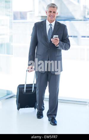 Businessman walking avec assurance et en utilisant son smartphone Banque D'Images