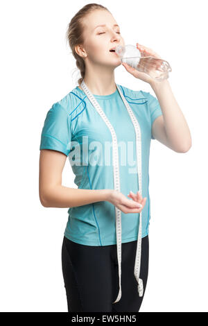 Beau Modèle de remise en forme féminine tenant une bouteille d'eau, portant un ruban à mesurer Banque D'Images